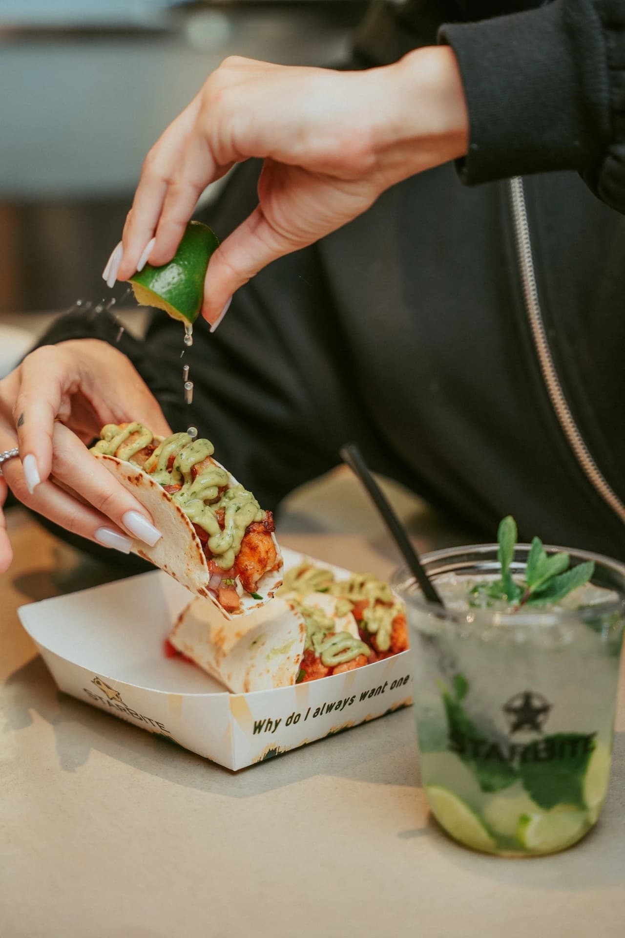 Squeezing lime over tacos with a cocktail